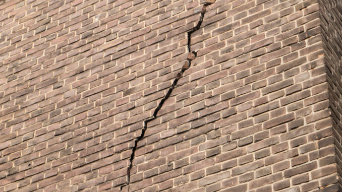 an old brick wall with a large crack